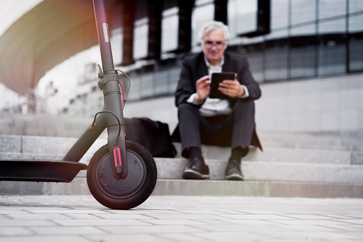 A man in a suit casually sits on a scooter, blending professionalism with a playful mode of transportation.