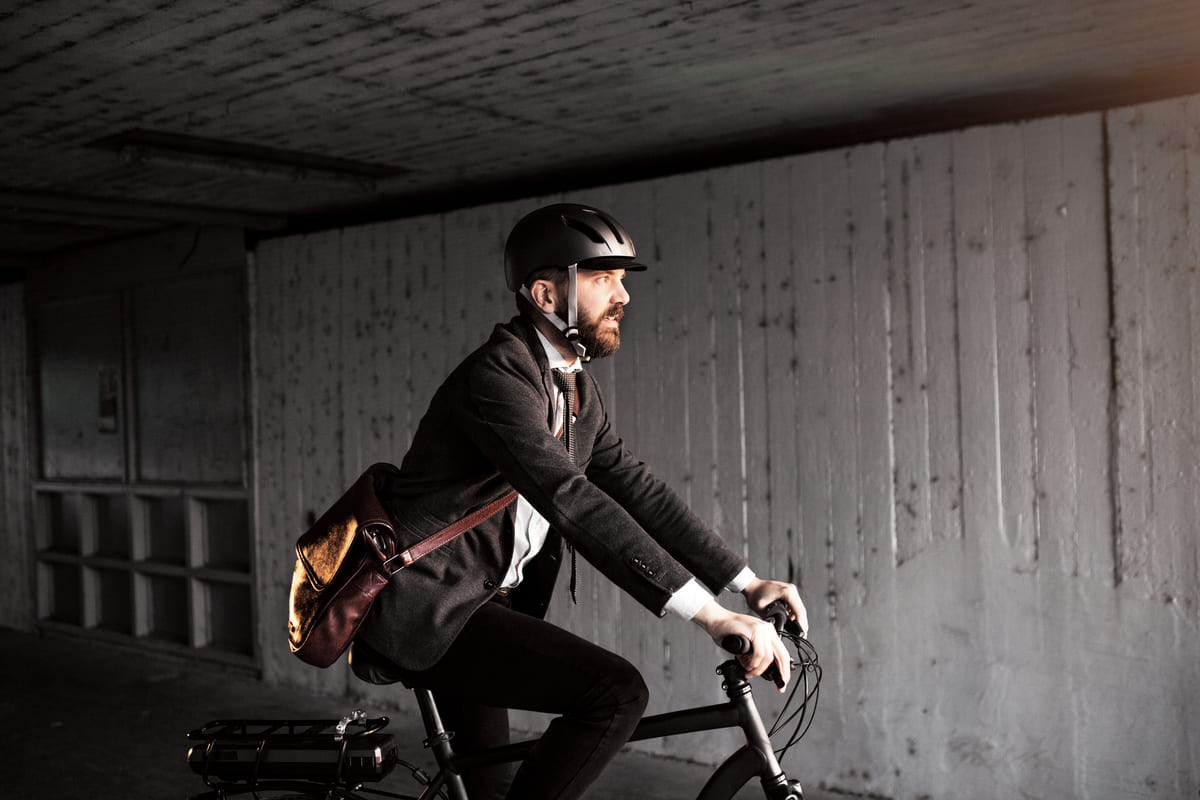 A man in a suit confidently rides a bike on a city street, showcasing a blend of professionalism and leisure.