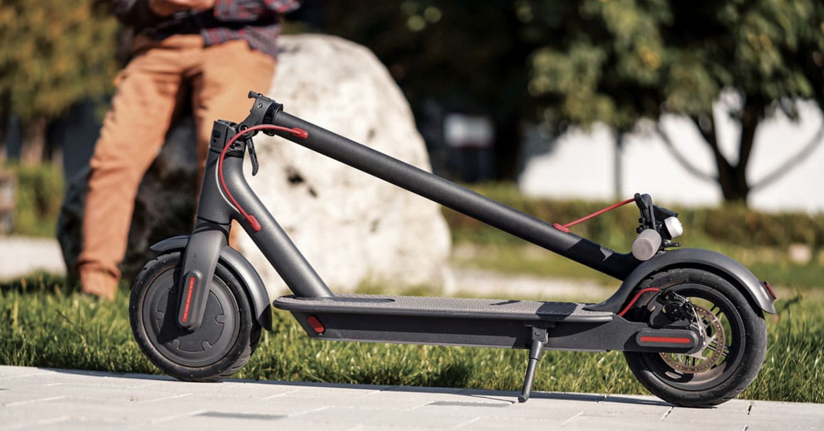 A man sits on a black and red scooter, ready to ride.