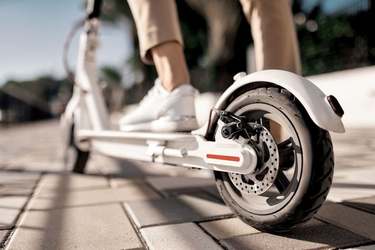 A person riding a white scooter on a sunny day, enjoying the outdoors.