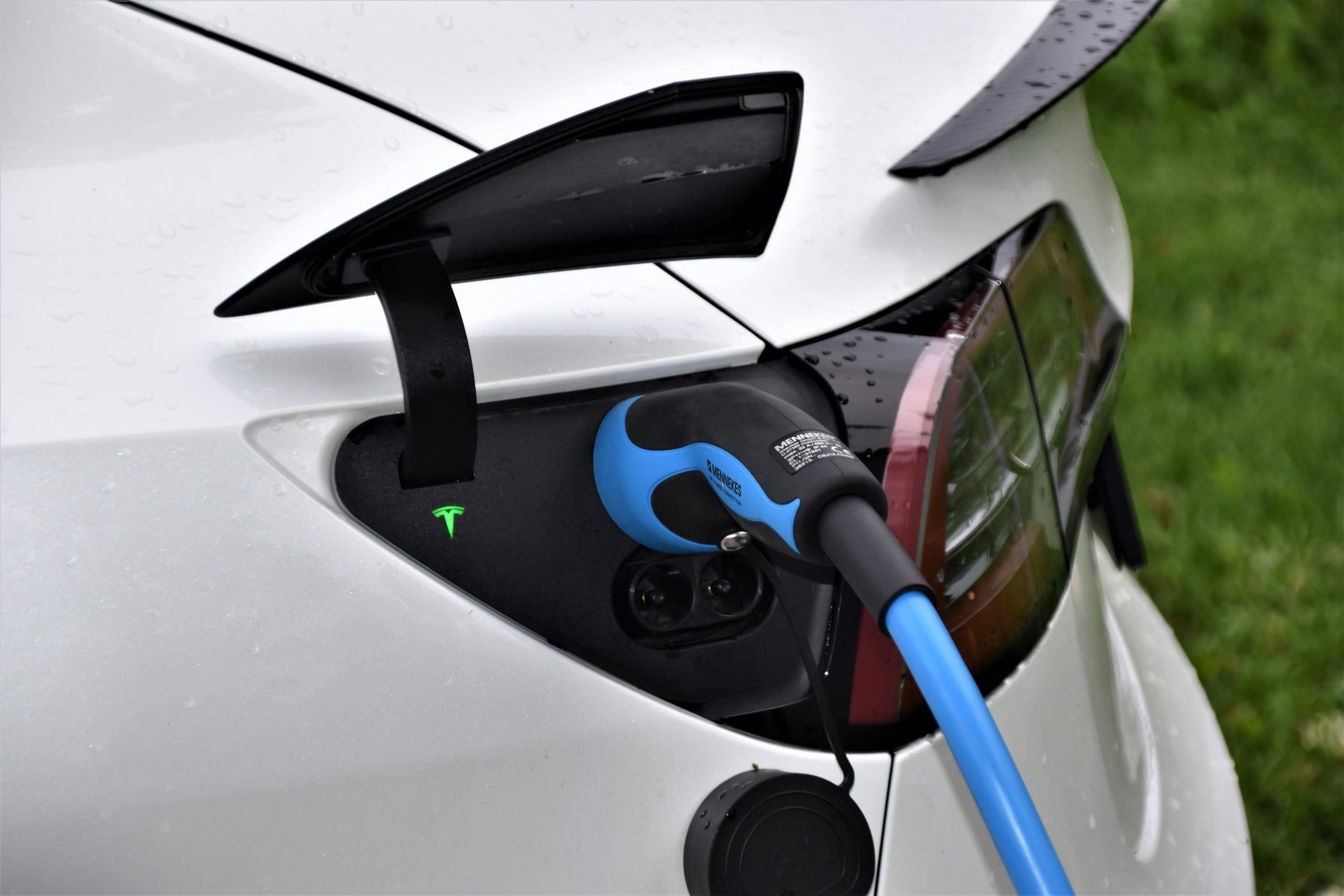 An electric car charging at a station, plugged into an electric charger for power.