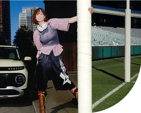 Hyundai-INSTER-grand-final-pic Split screen of a Hyundai INSTER parked in the city with a goal post for a lamp post and the MCG on the other side.