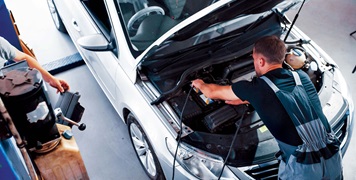 Auto mechanic working on car engine