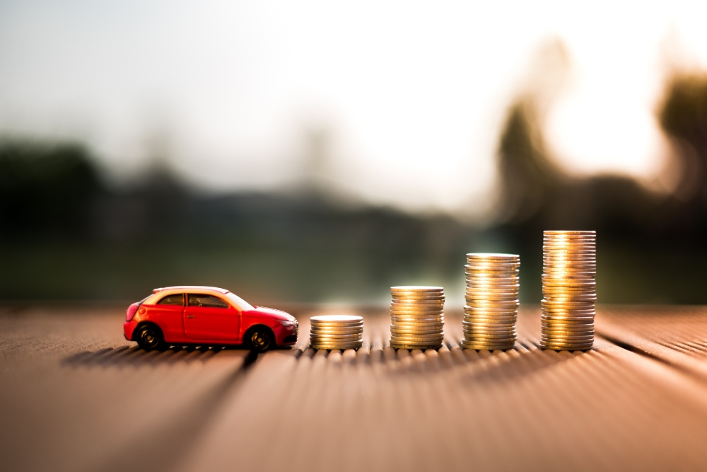 A small red car beside rising stacks of coins, representing the financial impact of ECOS Changes and the savings offered by UK salary sacrifice car schemes.