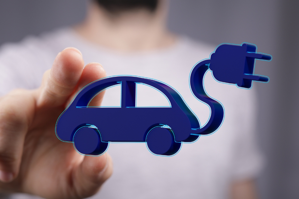 EV charging myths: A person holding a blue icon of an electric car with a charging plug.